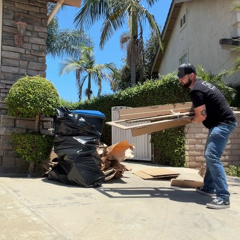 JunkFit crew loading cardboard and moving debris from a San Dimas driveway